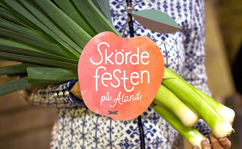 Ett gäng purjolökar hålls upp med en Skördefestlogotyp på